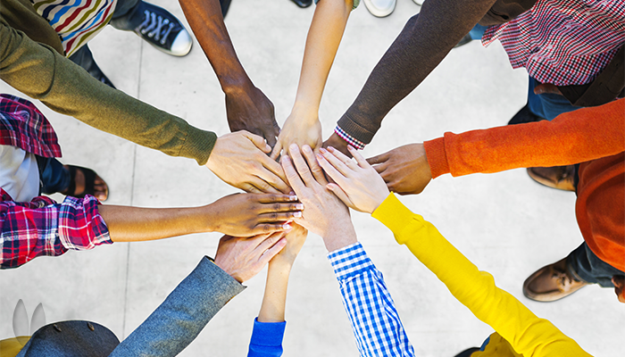 A diverse group of ten each reaching out with one hand.