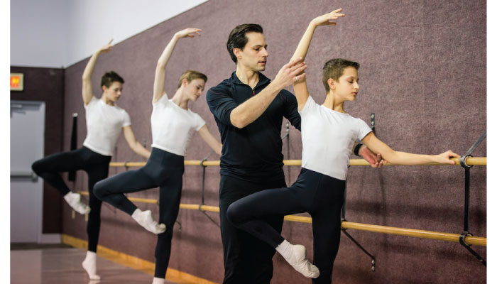 A dance coach correcting a dancers pose.