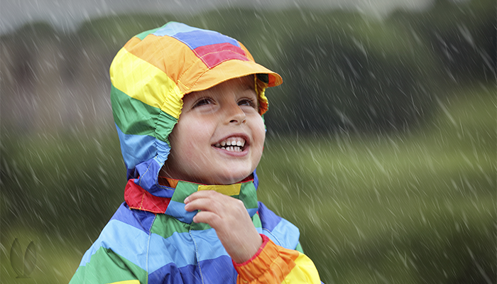 Smiling child dancing in the rain.