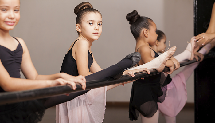 Girl dancers standing with one leg on a beam.