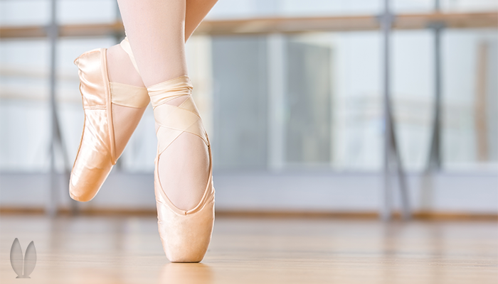 A dancer standing on tip of her right toes.