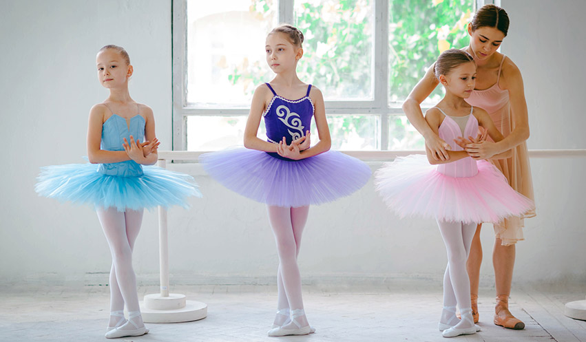 A dance instructor is adjusting the form of a student.