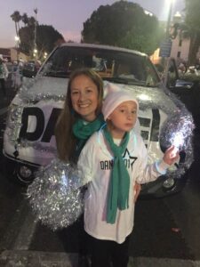 Happy mom and daughter with pompoms in a parade.