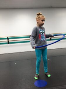 Dance student in a studio hula hooping.