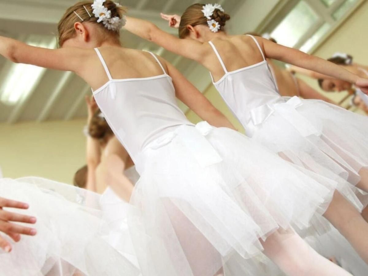 A youth ballet class begins to stretch before beginning their class