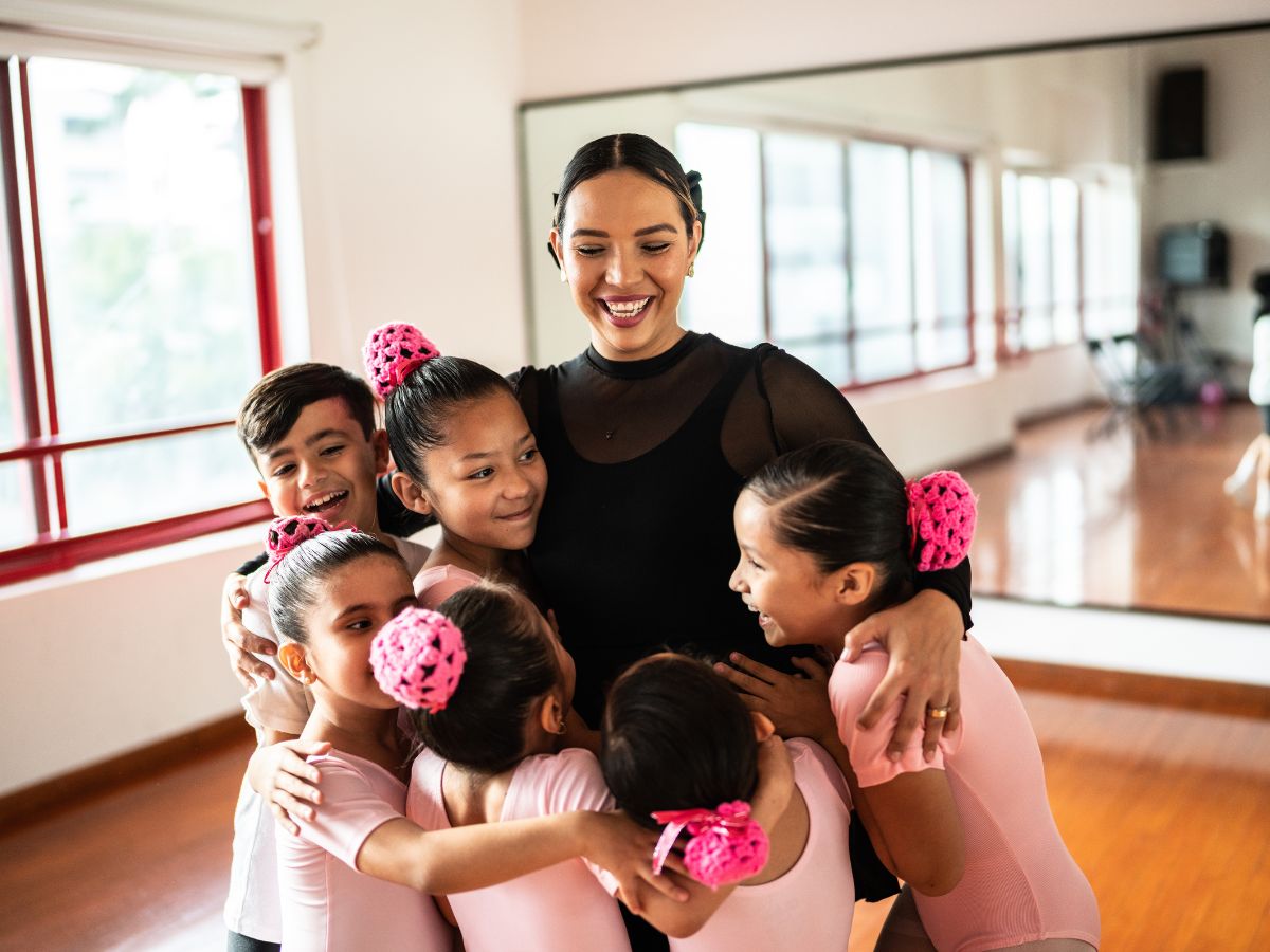 A dance teacher gives her students a group hug.