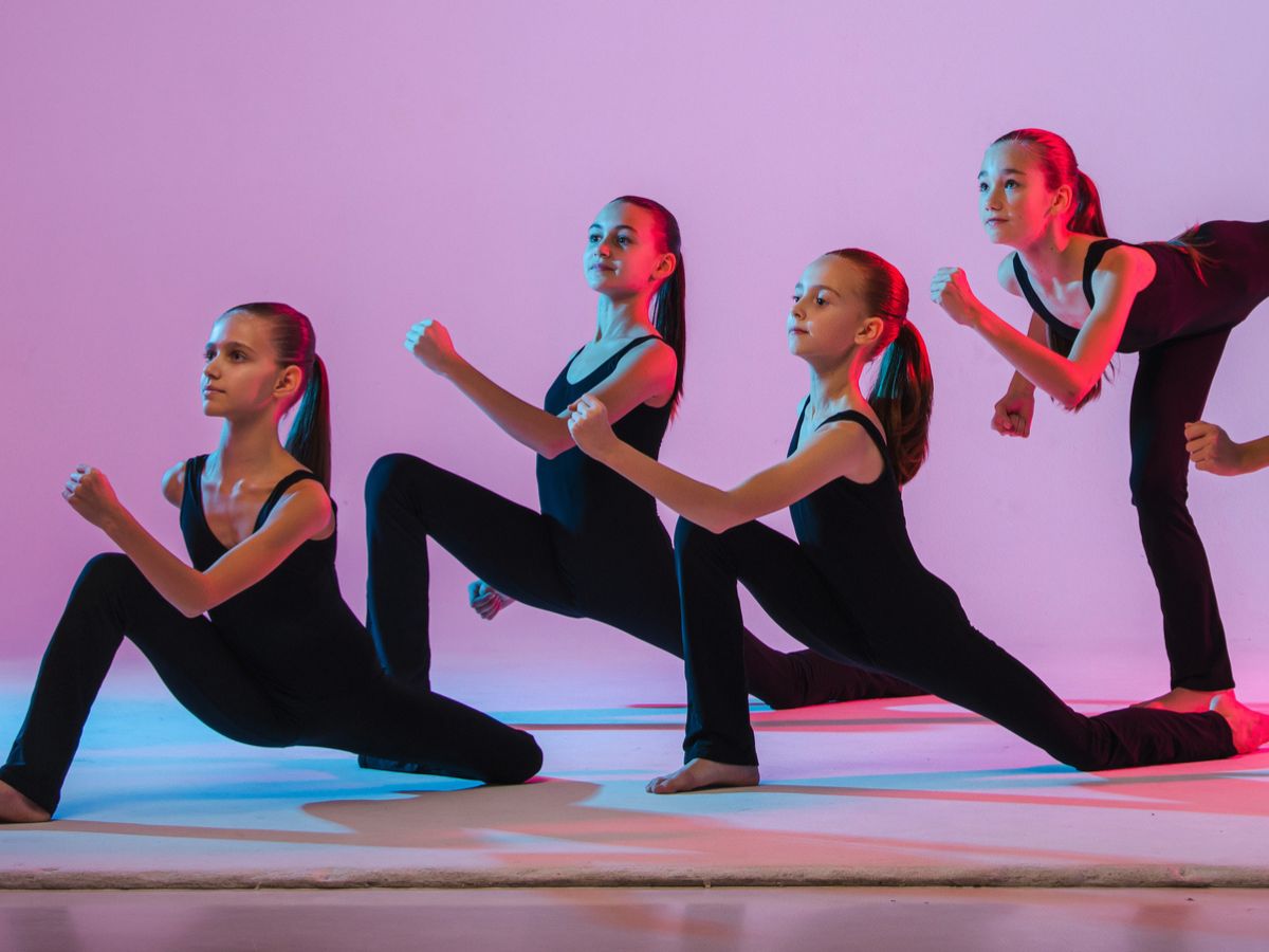 4 young dancers mid performance on a lit stage