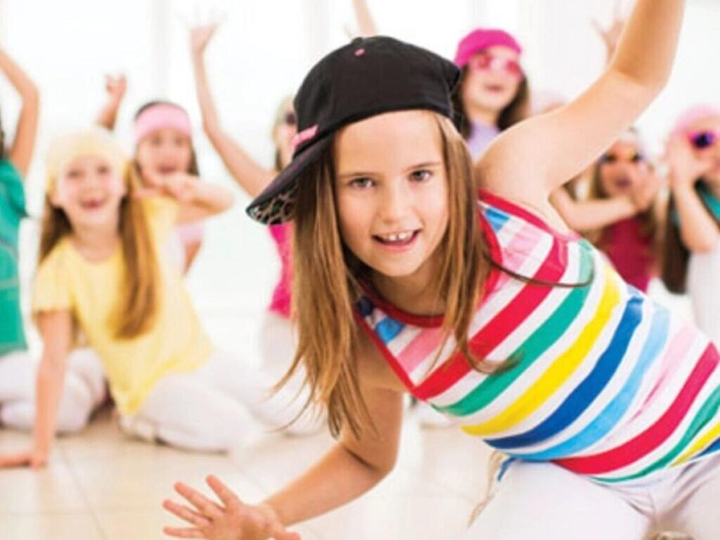 A girl in a baseball cap strikes a pose in a dance class