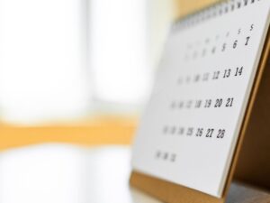 A monthly calendar sits on a desk.