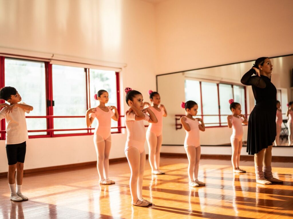 A dance teacher instructs her young students in a routine